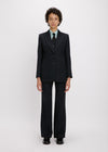 Person wearing a black suit with a white shirt and tie on a white background