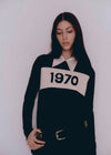 Person wearing a black and white sweater with '1970' print on a white background