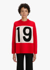 Person wearing a red sweater with a large black number '19' on a white background