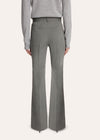 A model stands against a light studio background wearing a tailored light gray pinstripe suit with a white shirt, patterned tie, and black pointed shoes.
