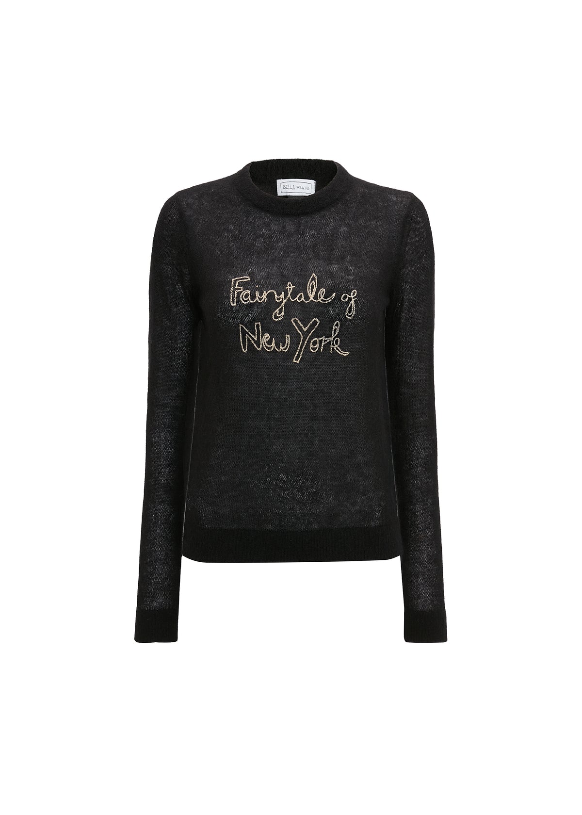 A model wearing a black long-sleeve knit sweater with a light pink collar and 'Fairytale of New York' embroidered in gold on the chest, styled with a light pink collared shirt and cream trousers against a light gray background.